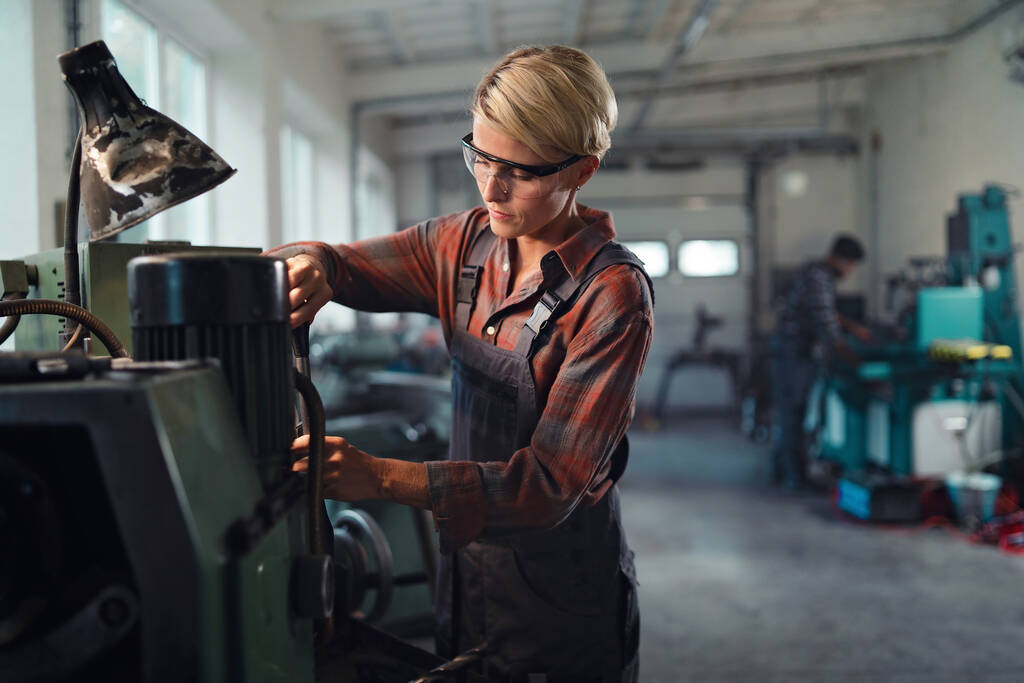 Portret dorosłej przemysłowej kobiety pracującej w warsztacie metalurgicznym. - Zdjęcie, obraz
