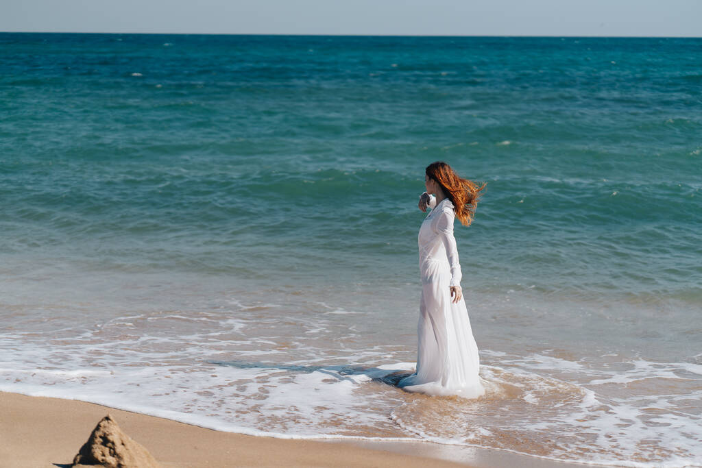 vrouw silhouet in een witte jurk door de oceaan frisse lucht - Foto, afbeelding