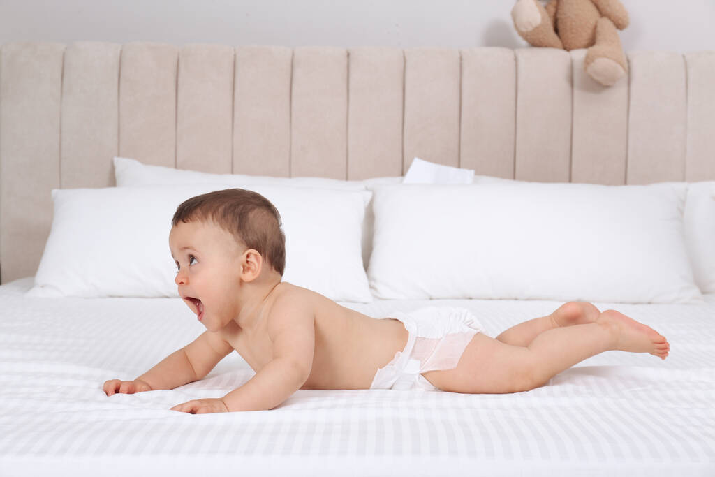 Evde beyaz yatakta kuru, yumuşak bebek bezi içinde şirin bir bebek. - Fotoğraf, Görsel
