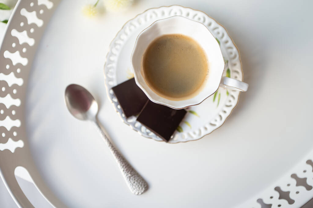 Κομψό φλιτζάνι καφέ espresso μαύρο με μαύρη σοκολάτα σε όμορφο λευκό δίσκο στην καφετέρια - Φωτογραφία, εικόνα