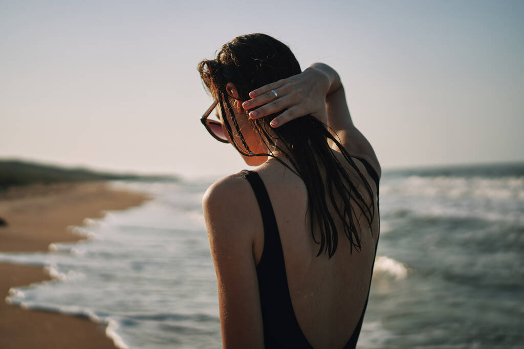 Frau im schwarzen Badeanzug spaziert am Strand Ozean Sommer - Foto, Bild