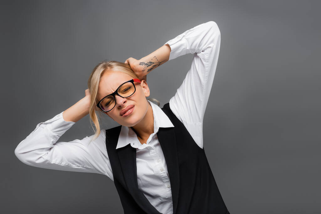 Businesswoman in eyeglasses suffering from headache isolated on grey  - Photo, Image