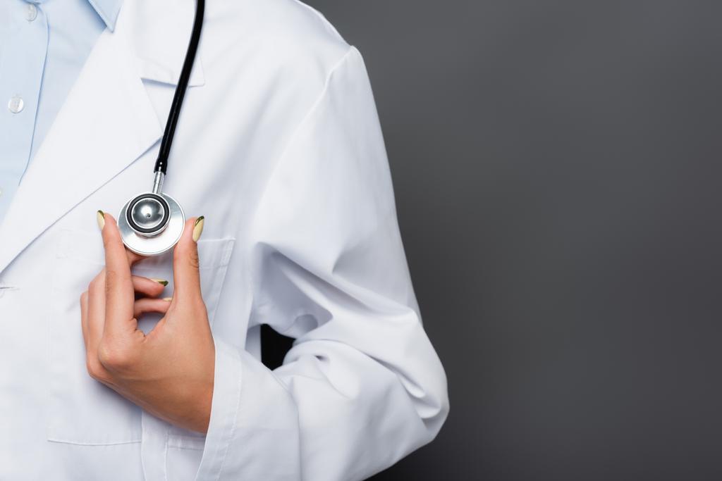Обрезанный вид врача, держащего стетоскоп изолированным на сером  - Фото, изображение