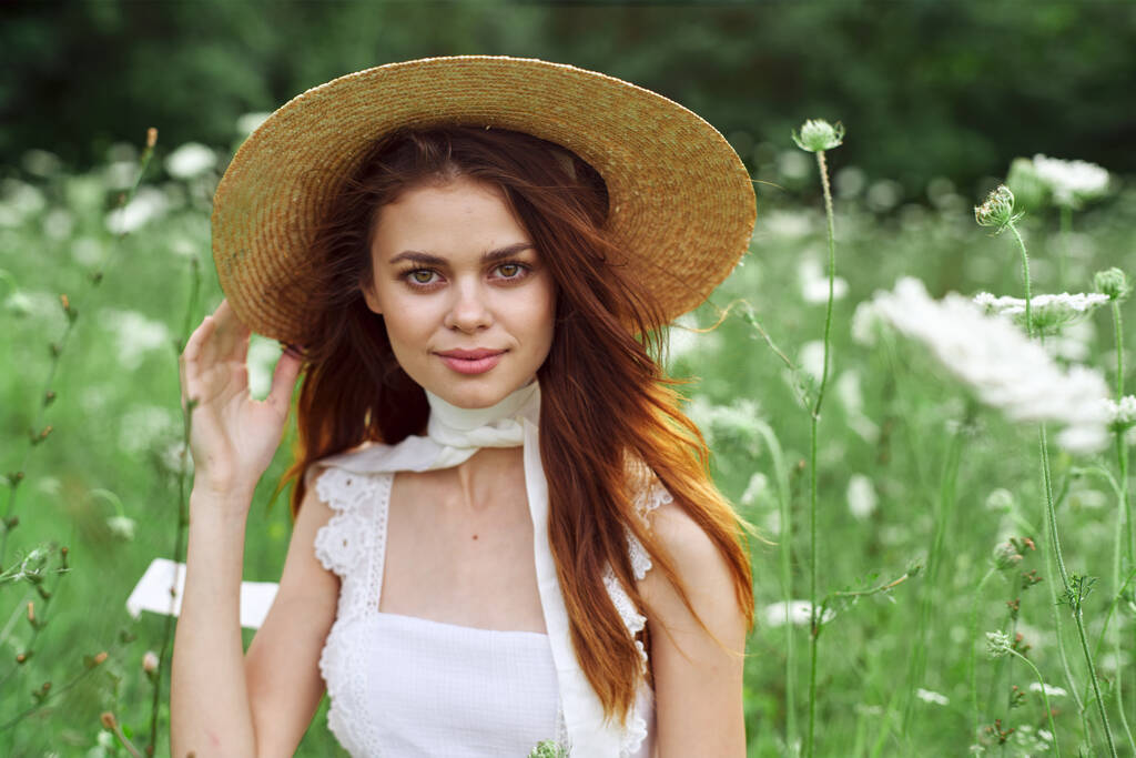 mooie vrouw in witte jurk en hoed poseren bloemen natuur - Foto, afbeelding