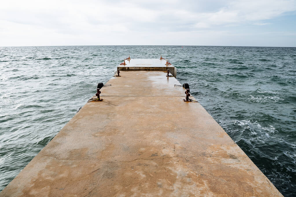 Muelle de hierro en el mar sin fin. Un viejo rompeolas en el mar. Un prometedor golpe de mar, cielos despejados y agua azul brillante. Foto de alta calidad - Foto, imagen