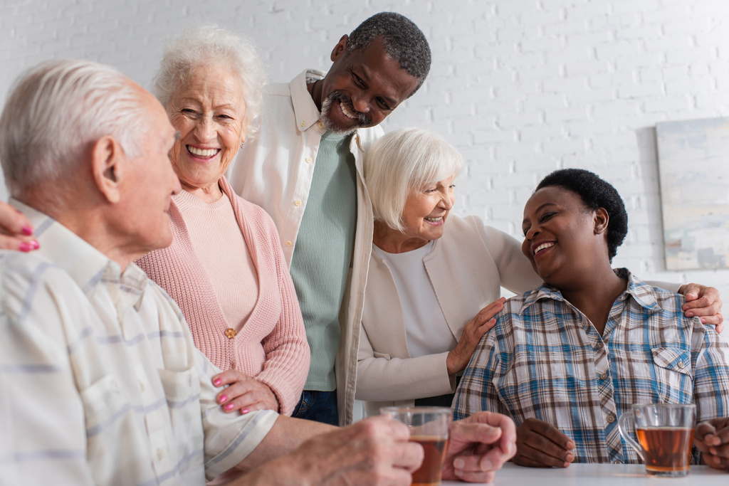 Позитивные межрасовые друзья разговаривают у чая в доме престарелых  - Фото, изображение