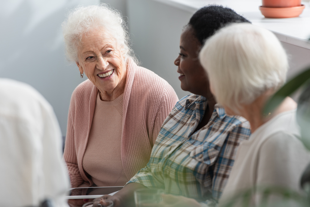 Többnemzetiségű idős nők digitális táblagéppel beszélgetnek az idősek otthonában  - Fotó, kép