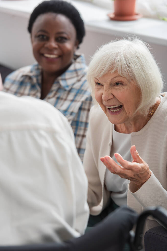 Θετική γυναίκα μιλάει σε θολή φίλη στο γηροκομείο  - Φωτογραφία, εικόνα