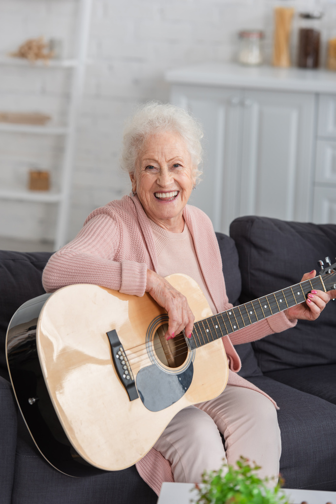 Ευτυχισμένη ηλικιωμένη γυναίκα που παίζει ακουστική κιθάρα στο γηροκομείο  - Φωτογραφία, εικόνα