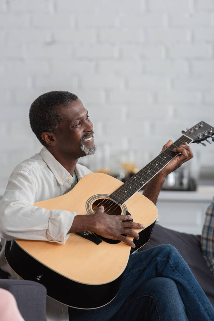 Zadowolony afrykański Amerykanin gra na gitarze akustycznej w domu opieki  - Zdjęcie, obraz
