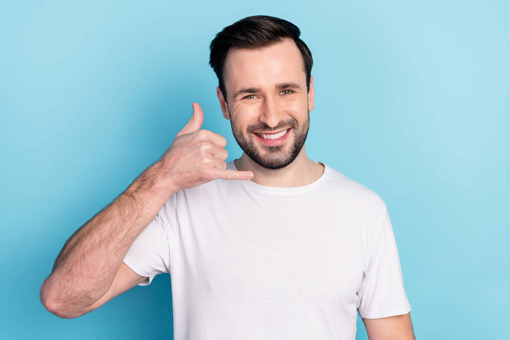 Portrait of attractive cheerful guy showing call me sign answer isolated over blue bright pastel color background. - Photo, Image