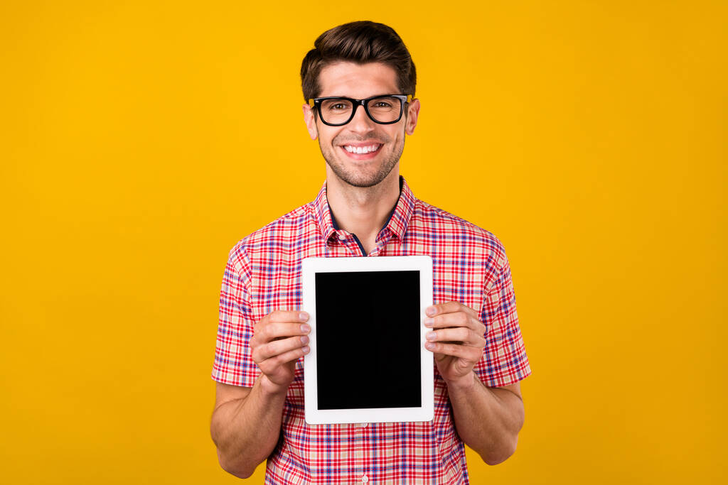 Portret atrakcyjnego wesołego faceta trzymającego w rękach tabletkę przestrzeń odizolowana od jasnożółtego tła - Zdjęcie, obraz