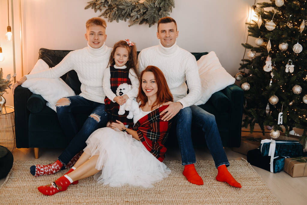 Close-up retrato de uma família feliz sentado em um sofá perto de uma árvore de Natal celebrando um feriado. - Foto, Imagem