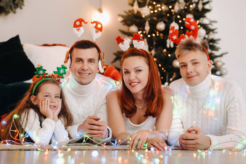 Κοντινό πλάνο πορτραίτο μιας ευτυχισμένης οικογένειας που κείτεται κοντά σε ένα χριστουγεννιάτικο δέντρο γιορτάζοντας τις διακοπές - Φωτογραφία, εικόνα