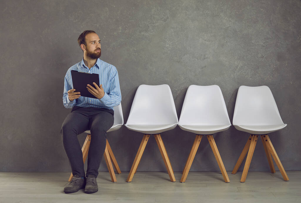 Gestresste blanke man voelt angst voor sollicitatiegesprek zittend op stoel - Foto, afbeelding