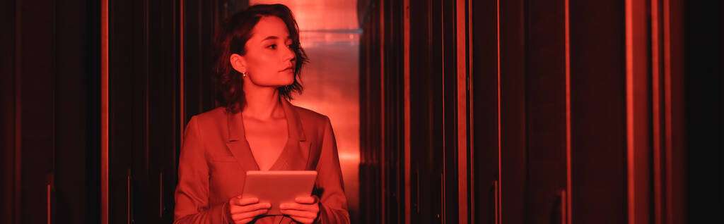 Nuori nainen digitaalinen tabletti tarkastellaan palvelimia datakeskuksen neon valo, banneri - Valokuva, kuva