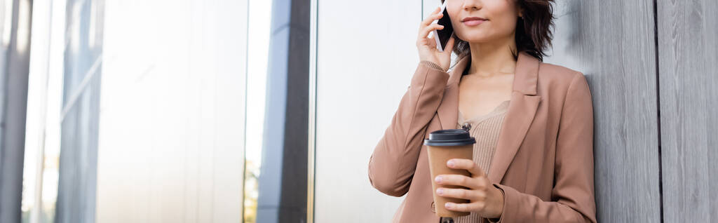 rajattu näkymä nuori nainen takeaway juoma puhuu matkapuhelimella ulkona, banneri - Valokuva, kuva
