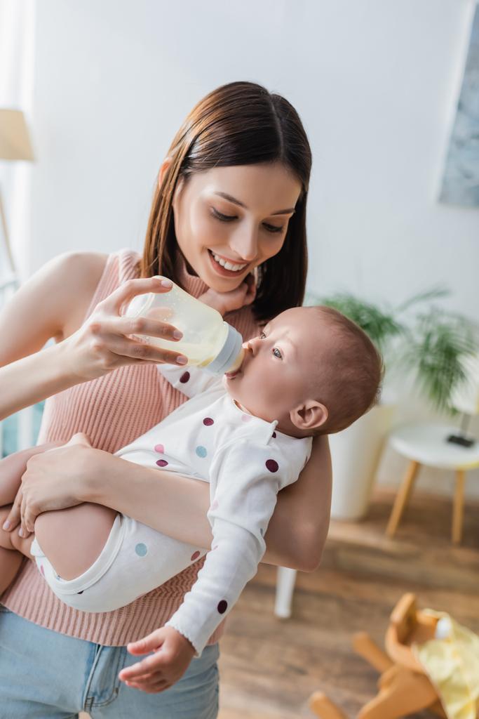 hymyilevä brunette nainen ruokinta lapsi poika maitoa kotona - Valokuva, kuva