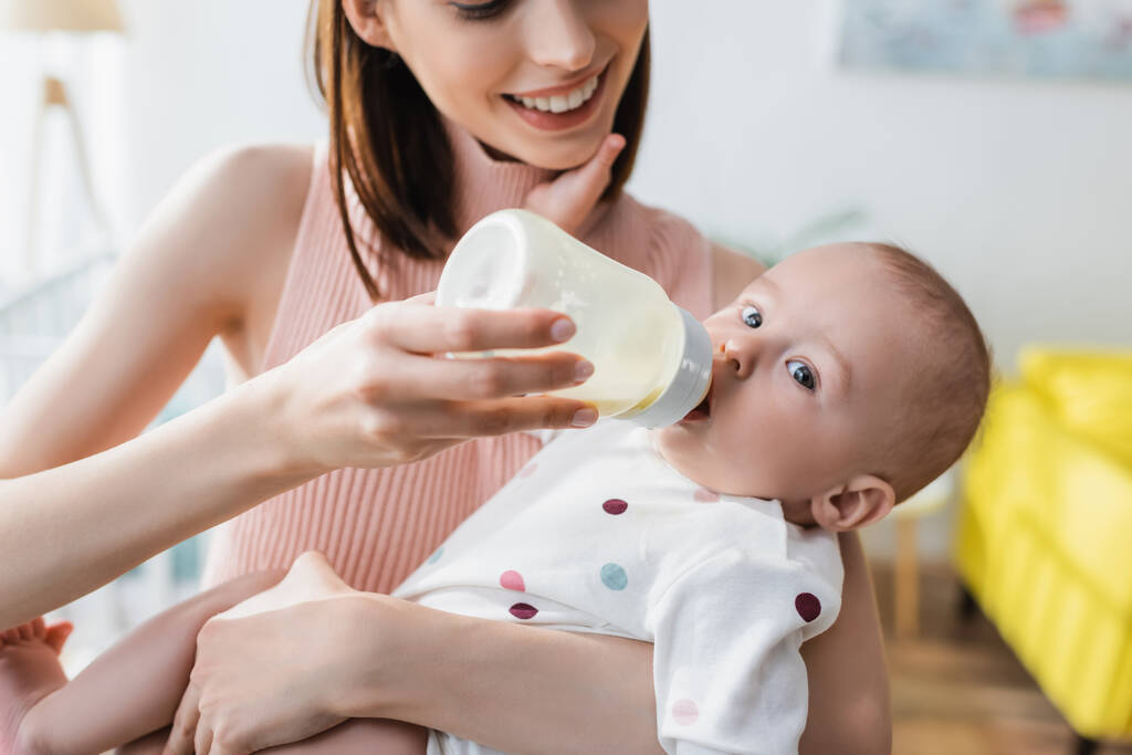 hämärtynyt nainen hymyilee ruokkiessaan lapsi poika tuttipullosta - Valokuva, kuva