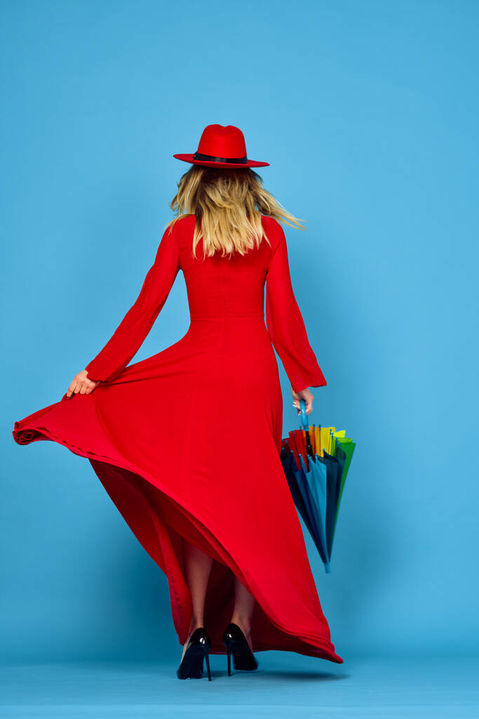 mujer en vestido rojo multicolor paraguas fondo azul - Foto, Imagen
