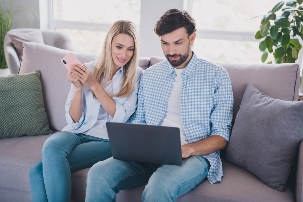 Foto de casal positivo sentar sofá compartilhar conta da família app usar roupas casuais em casa confortável dentro de casa - Foto, Imagem