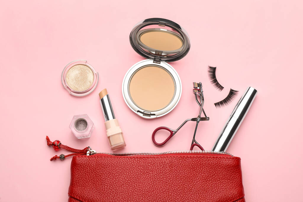 Boucleur de cils, sac cosmétique et produits de maquillage sur fond rose, pose plate - Photo, image