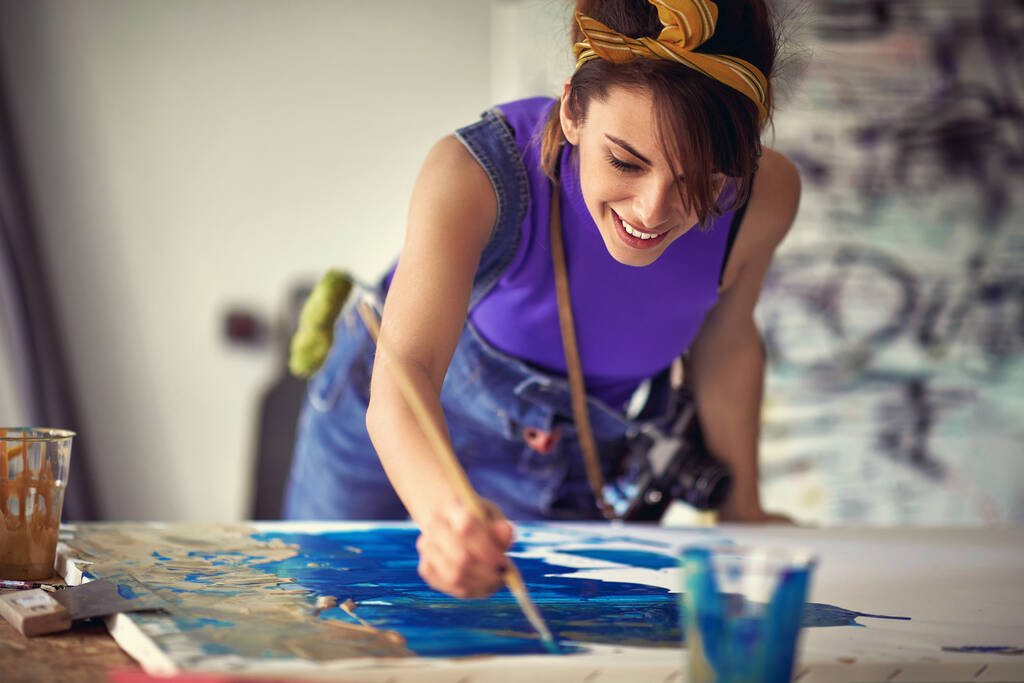 Közelkép egy fiatal női művészről, miközben kellemes légkörben dolgozik műtermében. Művészet, festmény, stúdió - Fotó, kép