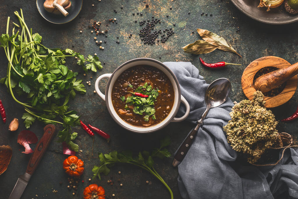 Cibo vegano. Ciotola con zuppa di lenticchie su sfondo tavolo cucina rustica con vari ingredienti. Vista dall'alto - Foto, immagini