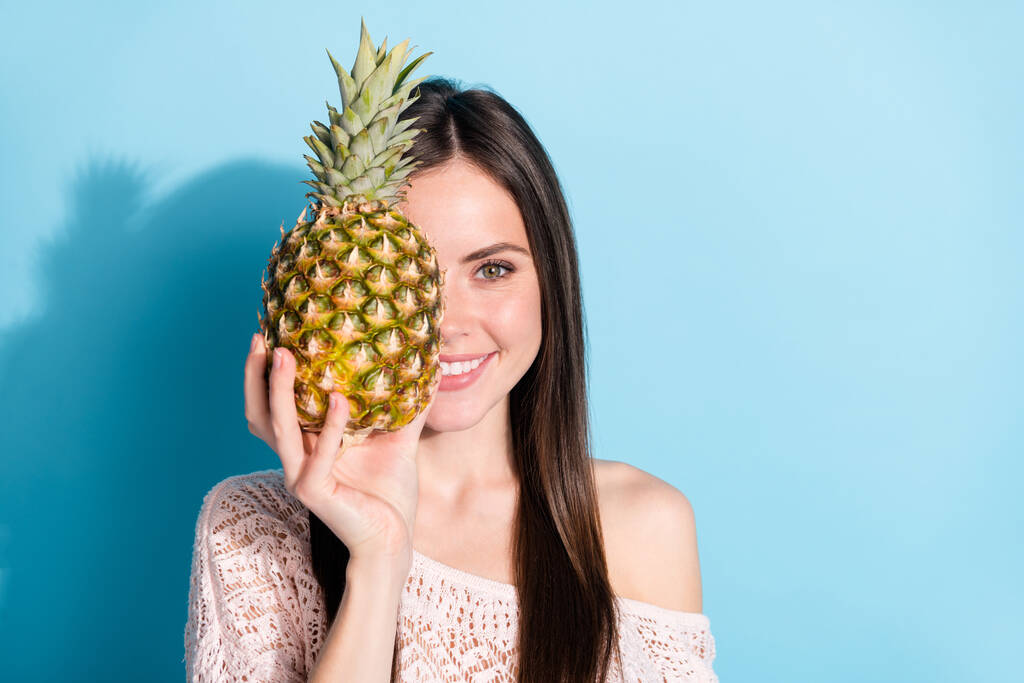 Foto di attraente bella giovane donna tenere ananas copertura mezza faccia isolata su sfondo di colore blu - Foto, immagini