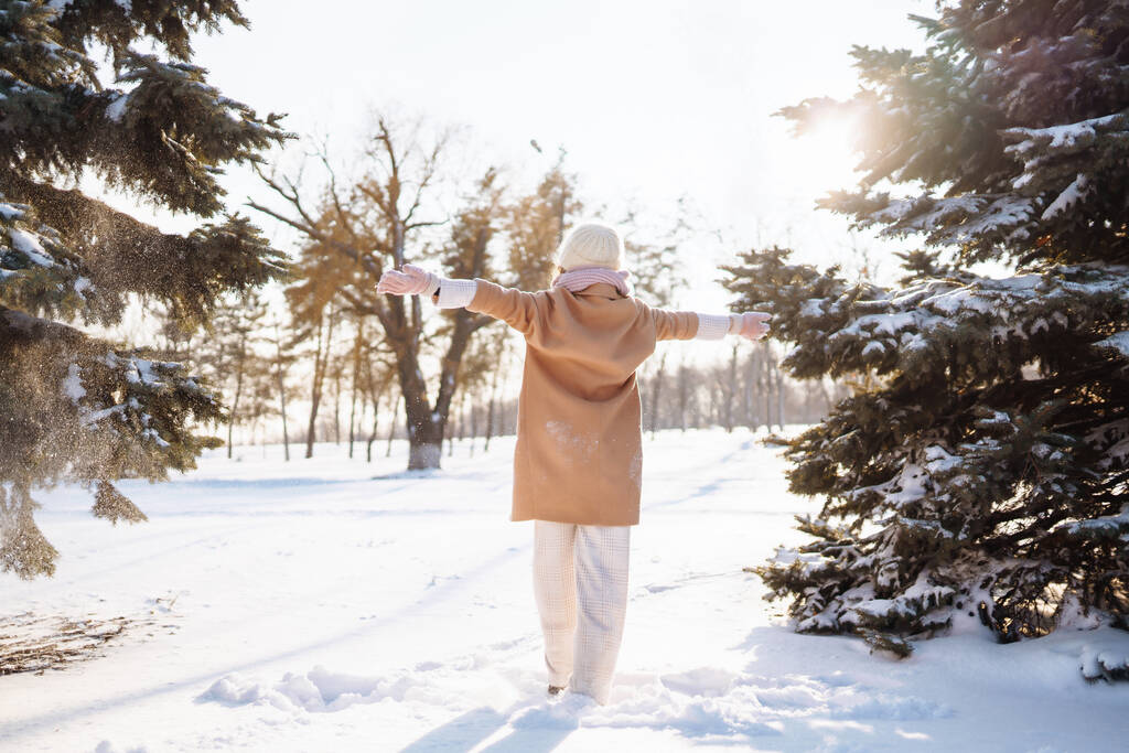 Boldog nő téli stílusú ruhákban sétál a havas erdőben. Természet, nyaralás, pihenés, utazási koncepció. - Fotó, kép