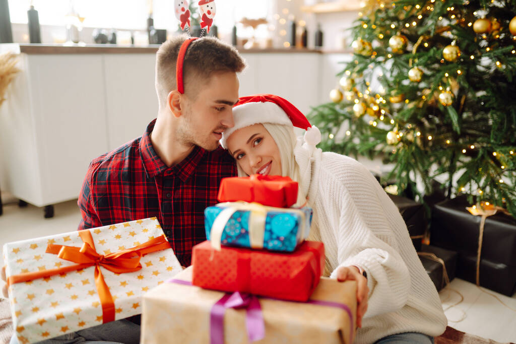 Un jeune couple heureux et aimant qui passe du temps ensemble près du sapin de Noël. Journée romantique. Vacances d'hiver. - Photo, image