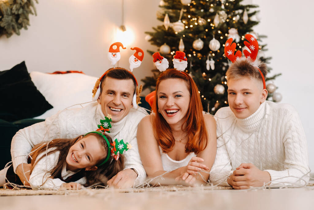 Retrato de cerca de una familia feliz tendida cerca de un árbol de Navidad celebrando unas vacaciones. - Foto, Imagen