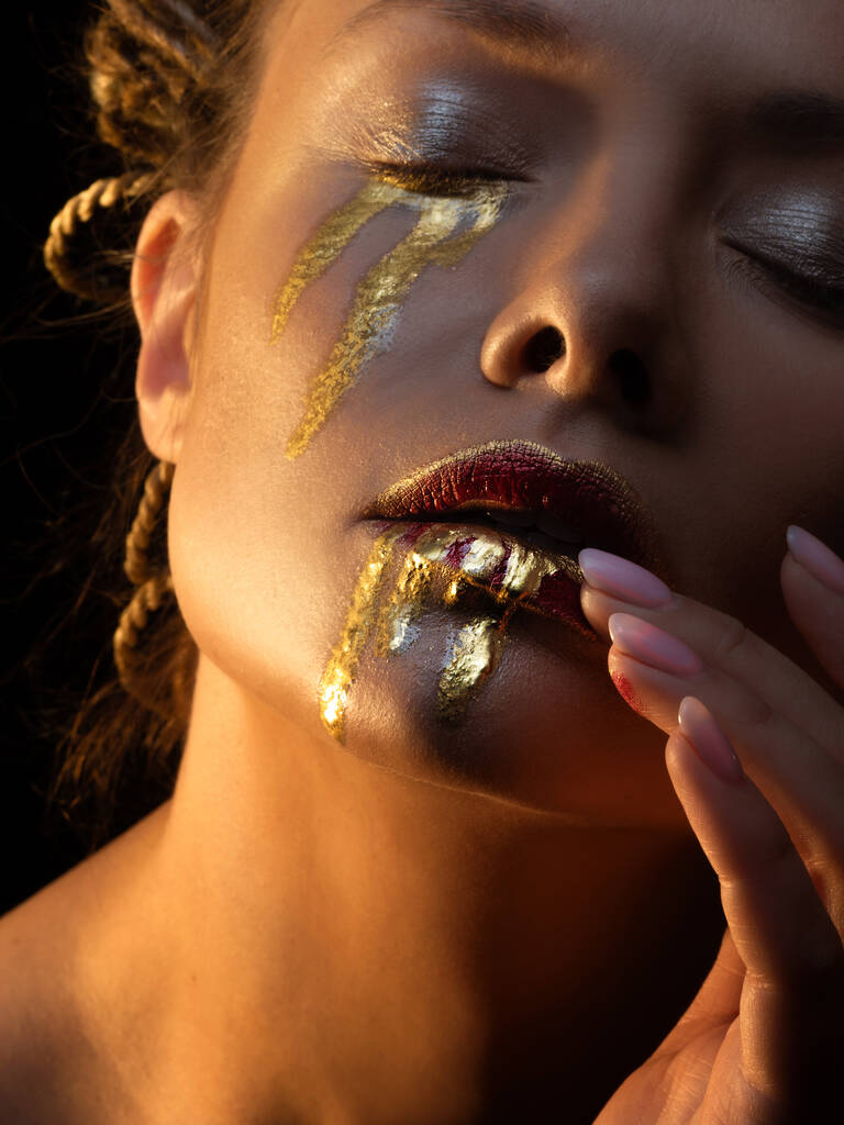 Goud op de huid, gezichtskunst en creatieve make-up, goud als tranen en bloed - Foto, afbeelding