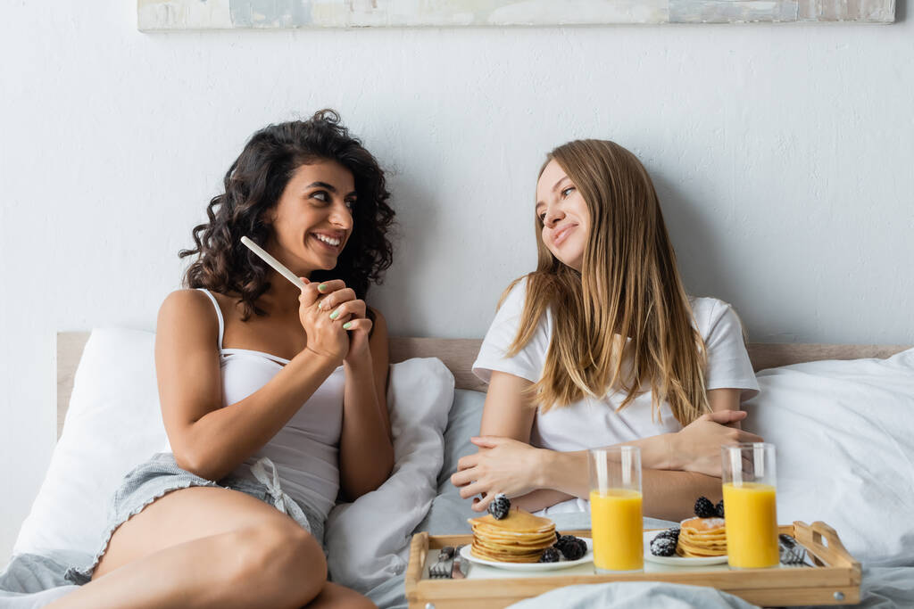 cheerful woman holding pregnancy test near girlfriend and tray with breakfast  - Photo, Image
