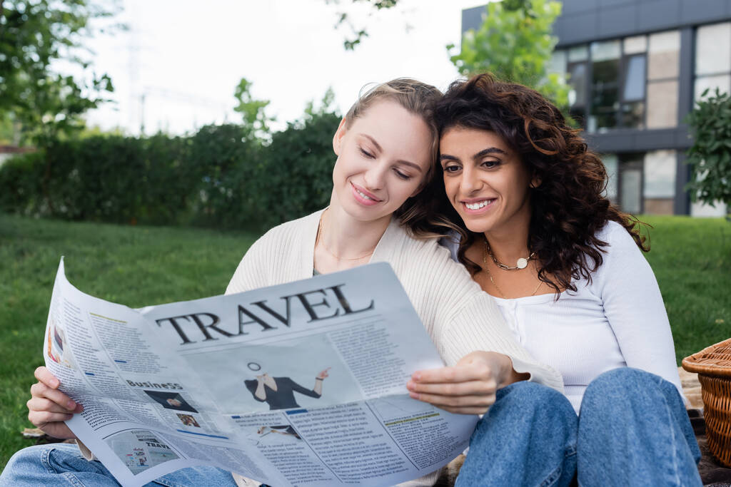 joyful lesbian couple reading travel newspaper in park  - Photo, Image