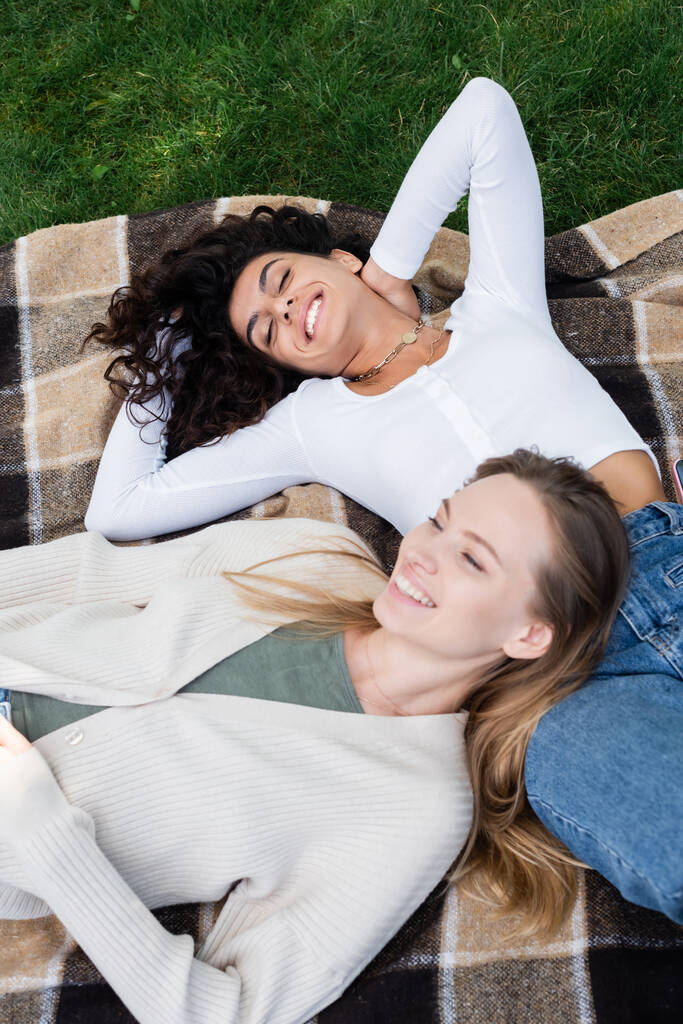top uitzicht van blij lesbische vrouwen liggen op geruite deken  - Foto, afbeelding