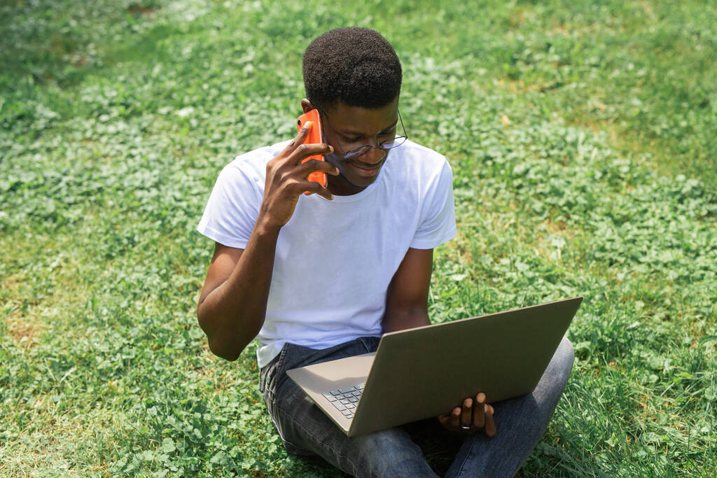 jong Afrikaans mannetje met mobiele telefoon en laptop - Foto, afbeelding