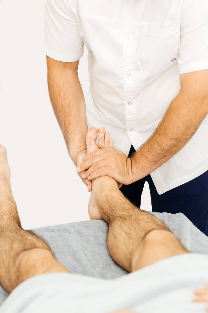 Οστεοπαθητικός εξετάζει το πόδι ενός άνδρα - Φωτογραφία, εικόνα