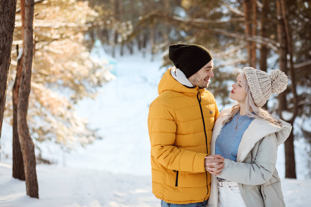 Happy couple i vêtements chauds passe du temps à l'extérieur dans la forêt d'hiver, espace de copie.  - Photo, image
