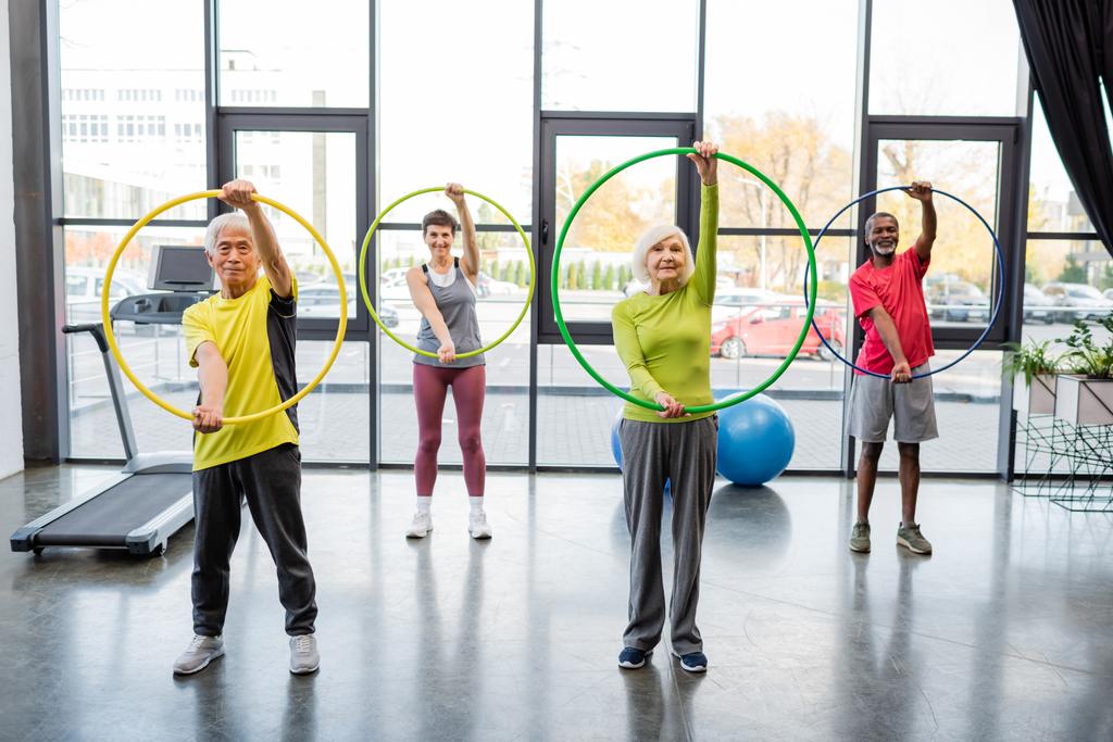 Entrenamiento multiétnico con hula hoops en el gimnasio  - Foto, Imagen