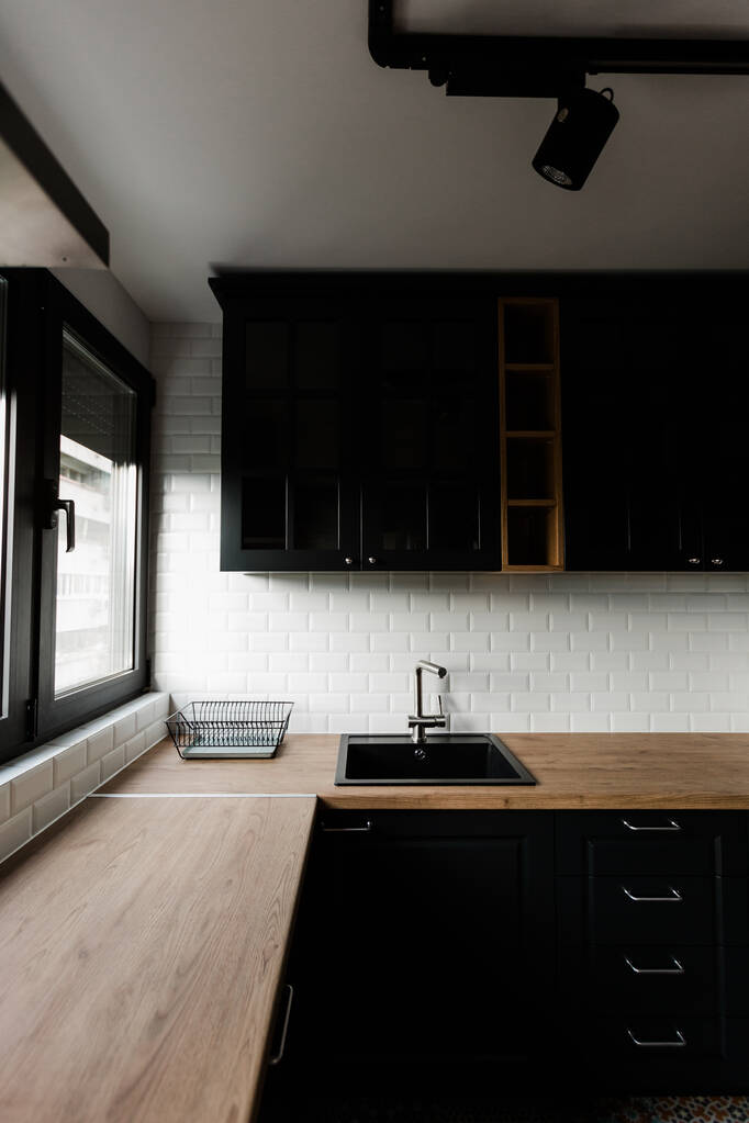 Een verticale opname van een moderne minimalistische keuken met witte bakstenen tegels en zwart meubilair - Foto, afbeelding