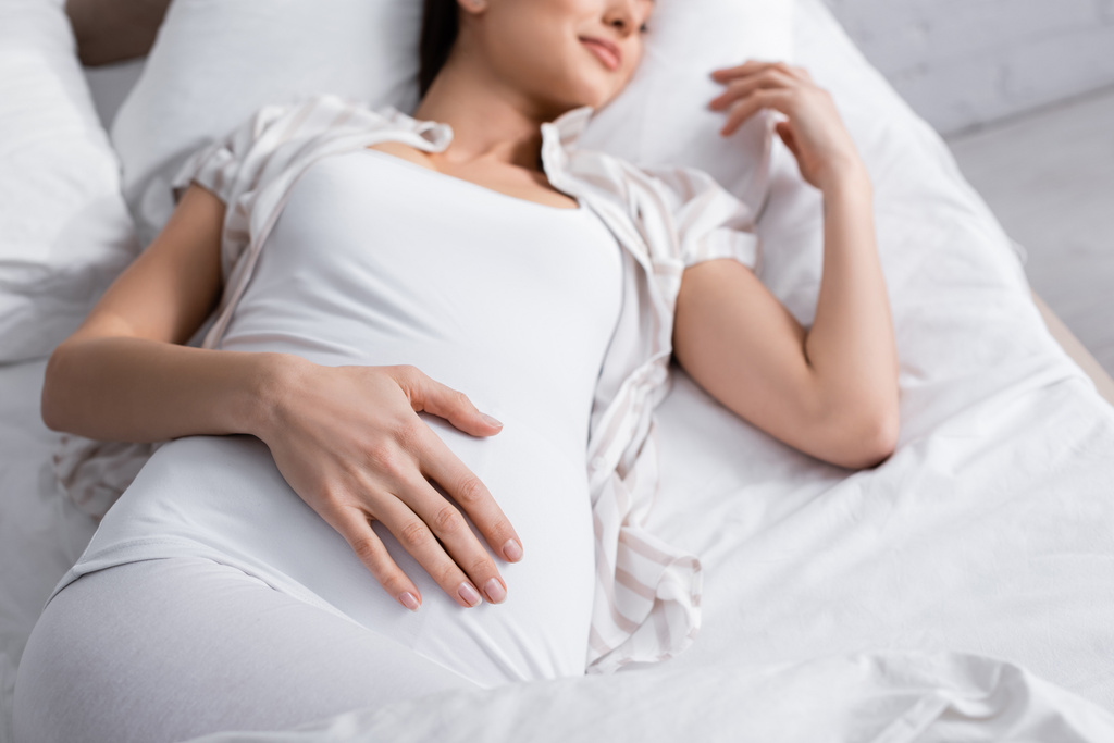 vista recortada de la mujer embarazada complacida en la cama - Foto, imagen
