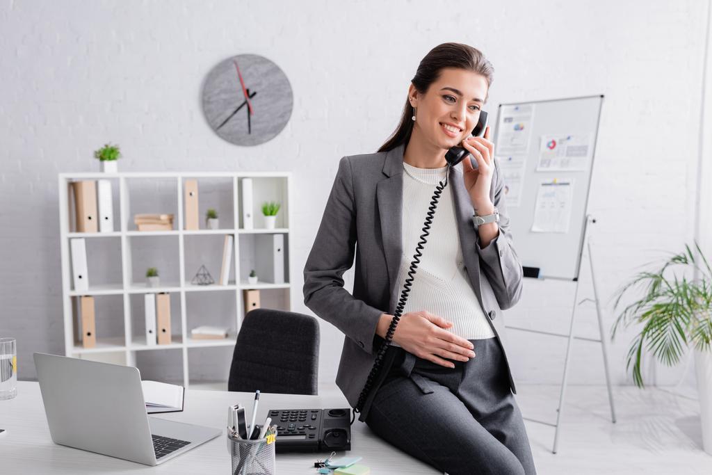 щаслива вагітна бізнес-леді розмовляє по ретро телефону
  - Фото, зображення