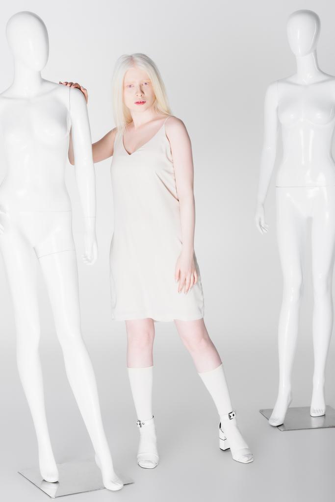 Pełna długość modelu albinos dotykając manekina na białym tle  - Zdjęcie, obraz