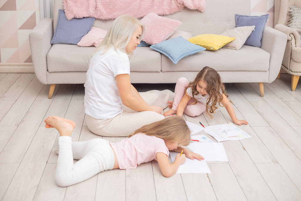 Madre e hijas se reúnen sentadas en el suelo en la sala de estar. Concepto de familia feliz. - Foto, imagen