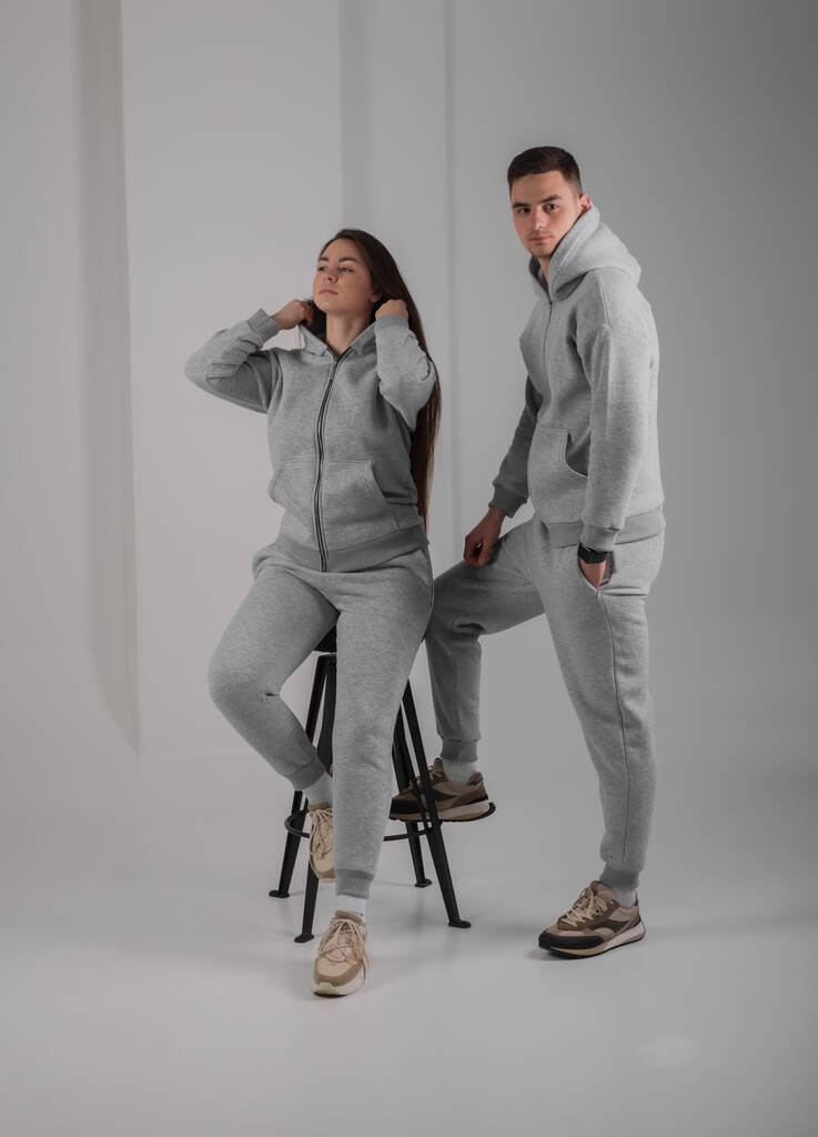Couple posant en studio portant des costumes à capuche gris - Photo, image