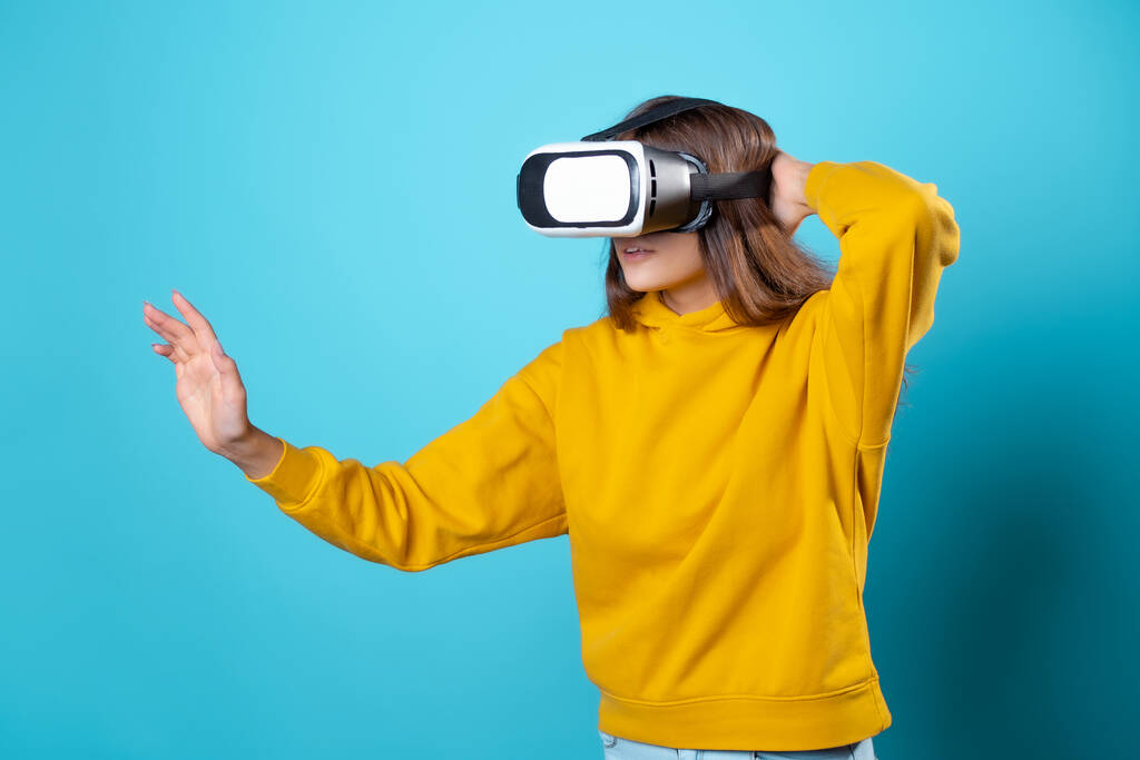 VR-геймер, молода жінка в молодіжному вбранні, використовує шолом віртуальної реальності
. - Фото, зображення