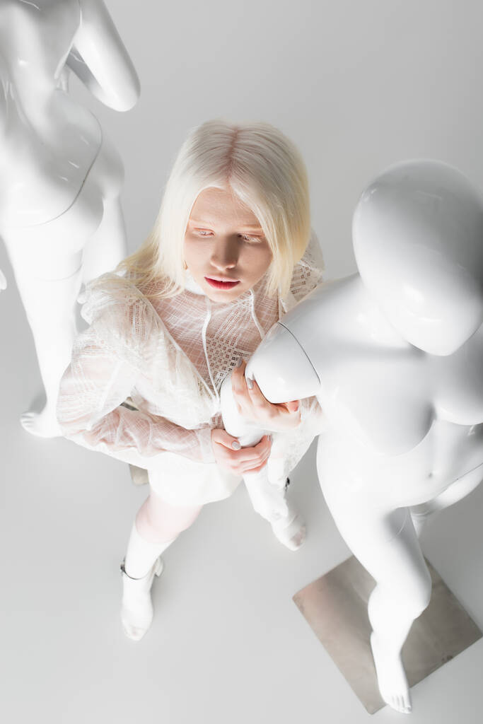 Vue aérienne de femme albinos touchant mannequin sur fond blanc  - Photo, image