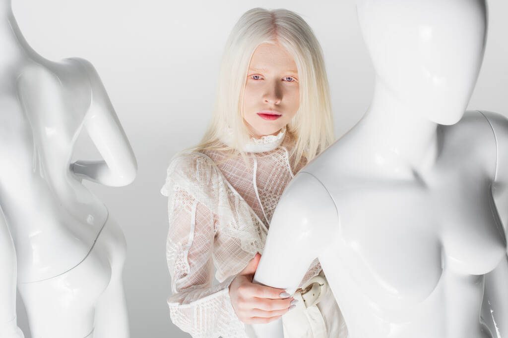 Joven modelo albino en blusa posando cerca del maniquí aislado en blanco  - Foto, imagen