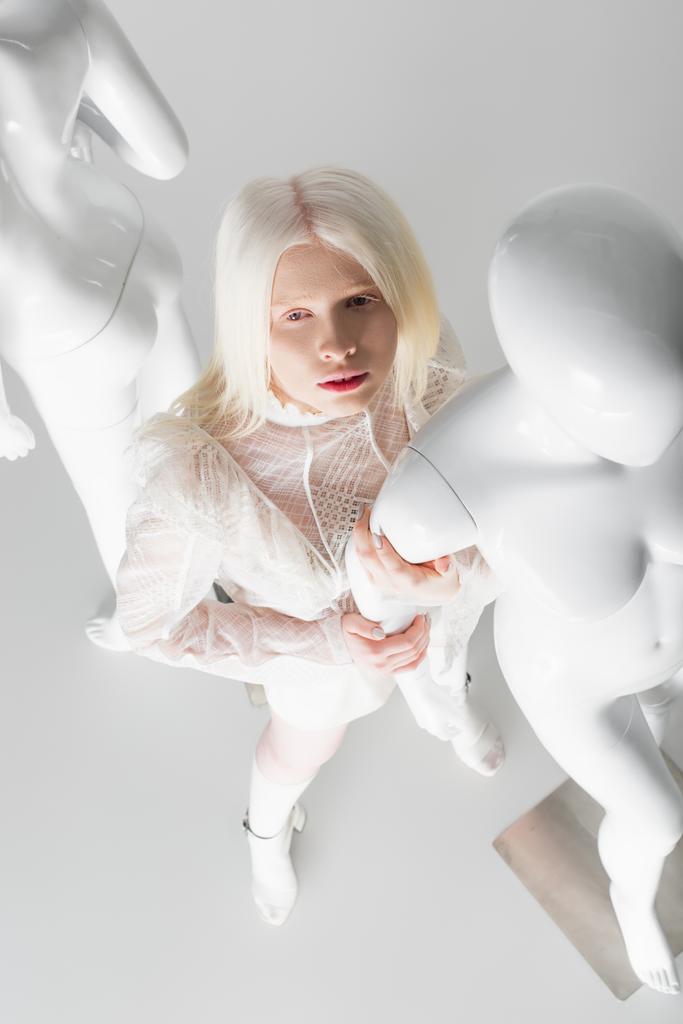 Visão aérea da mulher albina na moda em blusa de pé perto do manequim no fundo branco  - Foto, Imagem